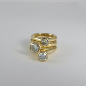 three solitair simple cast rings in yellow gold with proud set brilliant diamonds