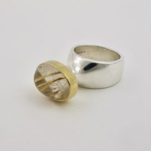 Oval cabochon Rutilated quartz in a gold setting on polished Silver Plinth ring