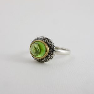 green tourmaline in gold on dimpled silver pebble