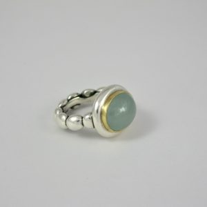 Milky oval aquamarine set in gold on silver pebble ring