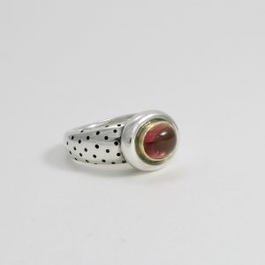 Peachy pink tourmaline cabochon set in gold with chunky silver surround on a wide polka dot heavy silvershank